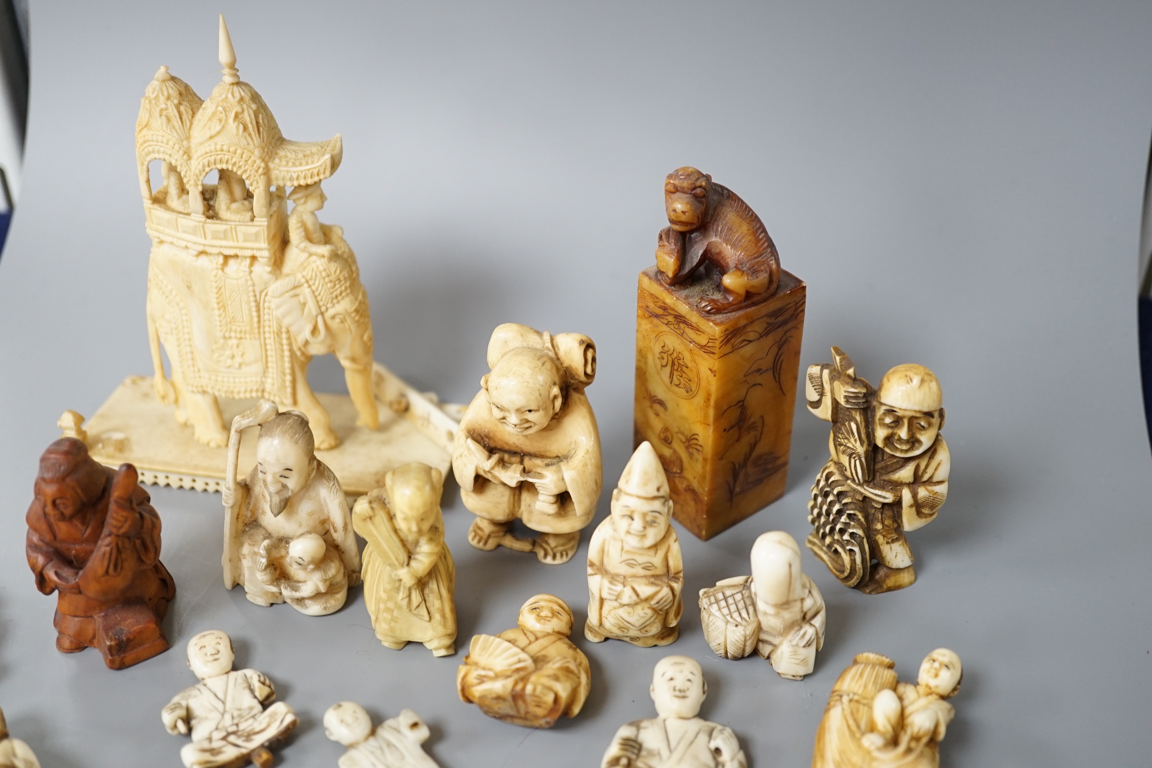 A collection of various ivory carvings including netsuke, a soapstone seal and carved wood netsuke